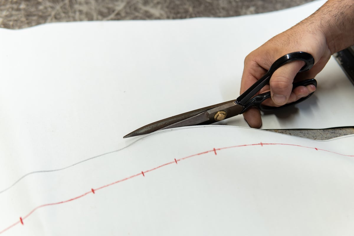 Upholsterer cutting pieces of leather with scissors to repair a